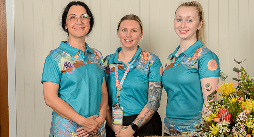 Three First Nations midwives stand proudly behind a display of native flowers and traditional artifacts at welcome baby to community