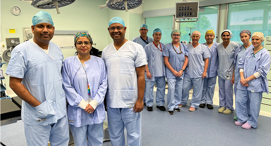 A day surgery team in scrub suits stands together in a hospital procedure room, ready for patient care.